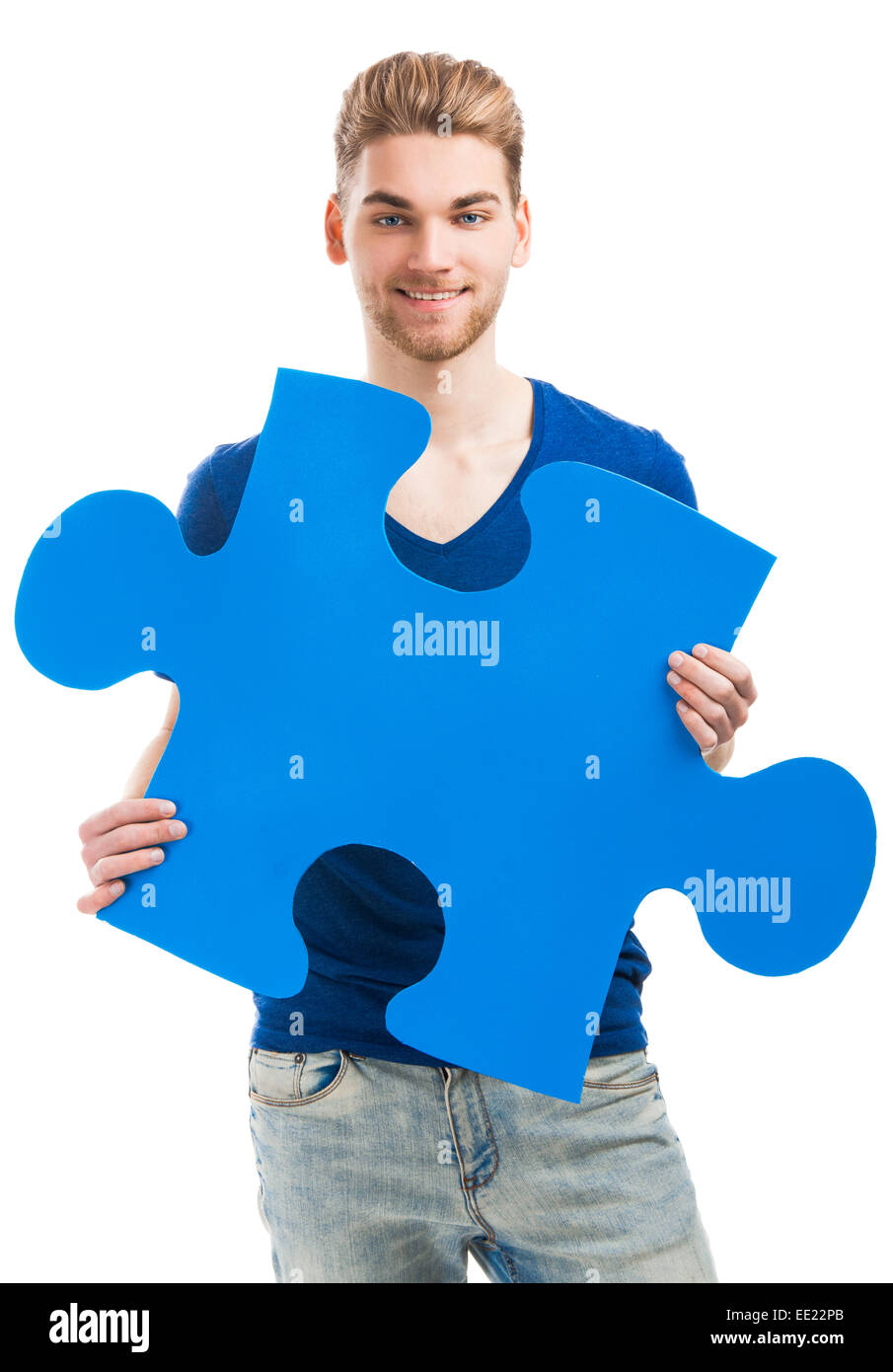 Buona ricerca giovane tenendo un puzzle blu pezzo, isolato su uno sfondo bianco Foto Stock