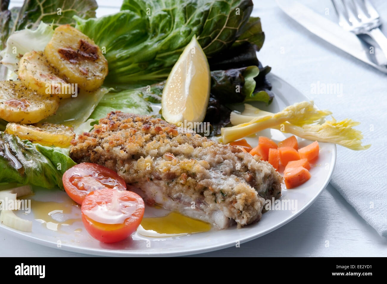 Filetti di merluzzo impanato e cotto al forno con patate e insalata per guarnire Foto Stock