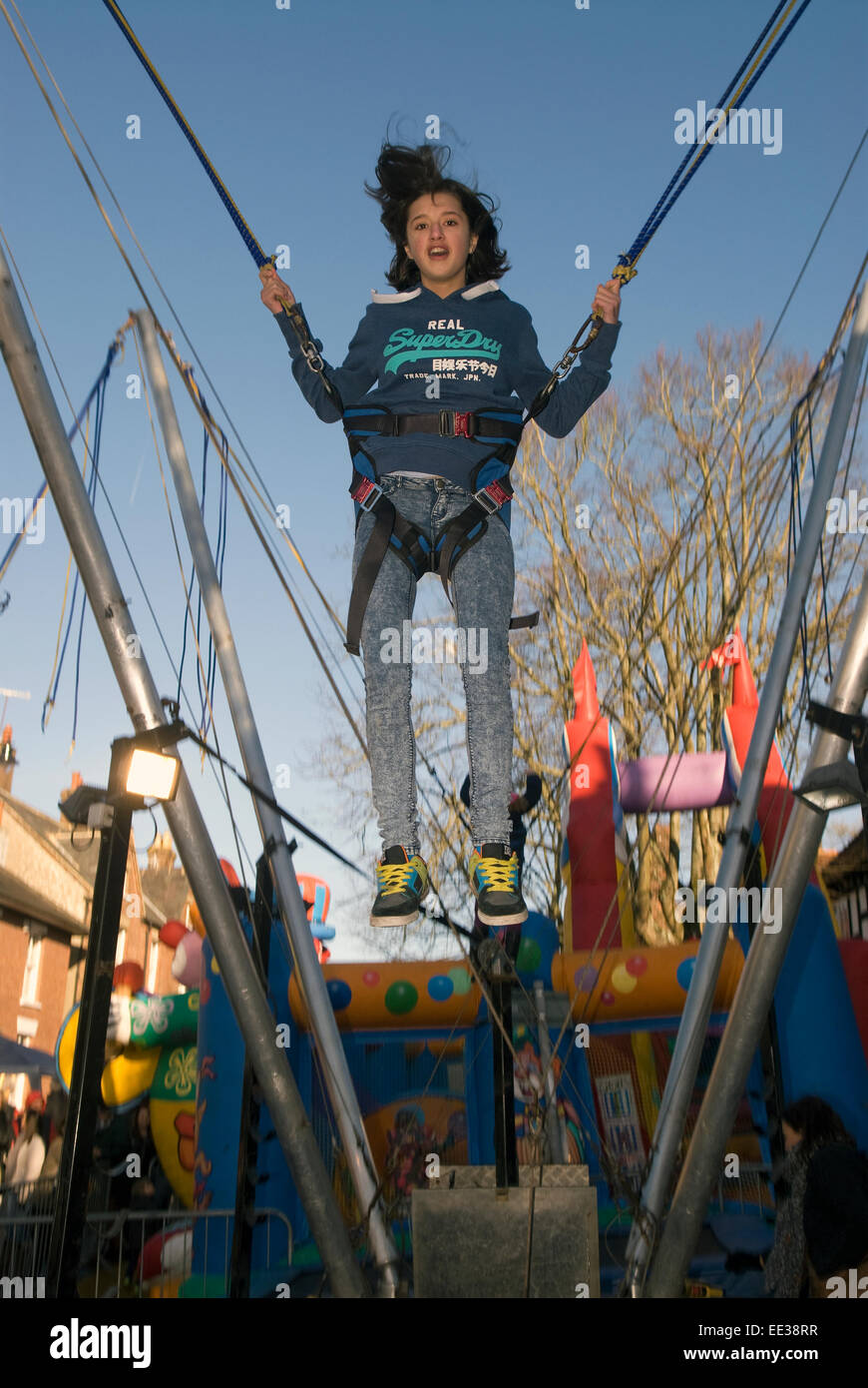 12 anno vecchia ragazza divertirsi sul trampolino bunjee presso un mercato di natale, High Street, Haslemere, Surrey, Regno Unito. dicembre 2014. Foto Stock