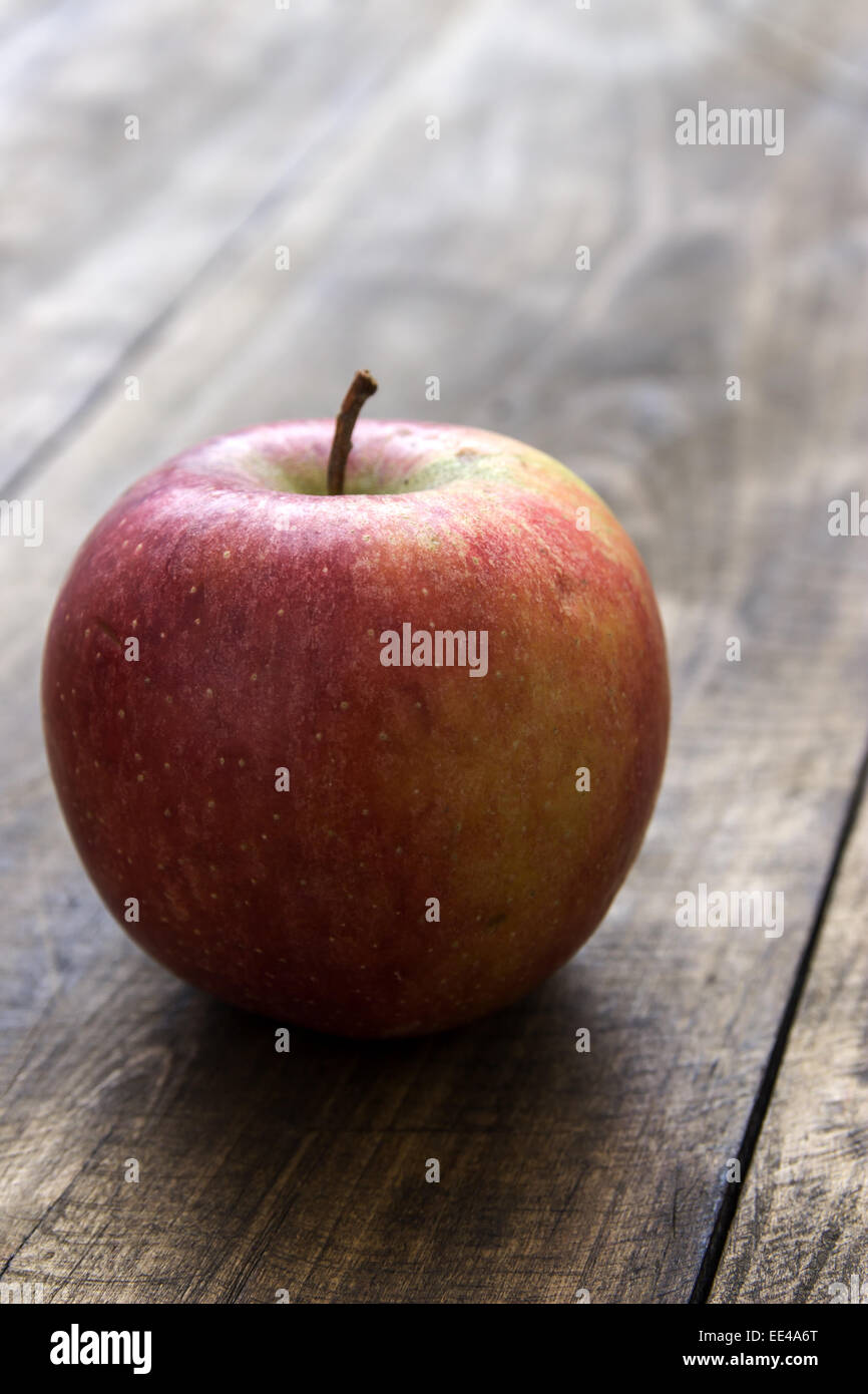 Rosso fresco apple organico sul vecchio tavolo in legno, retroilluminato Foto Stock