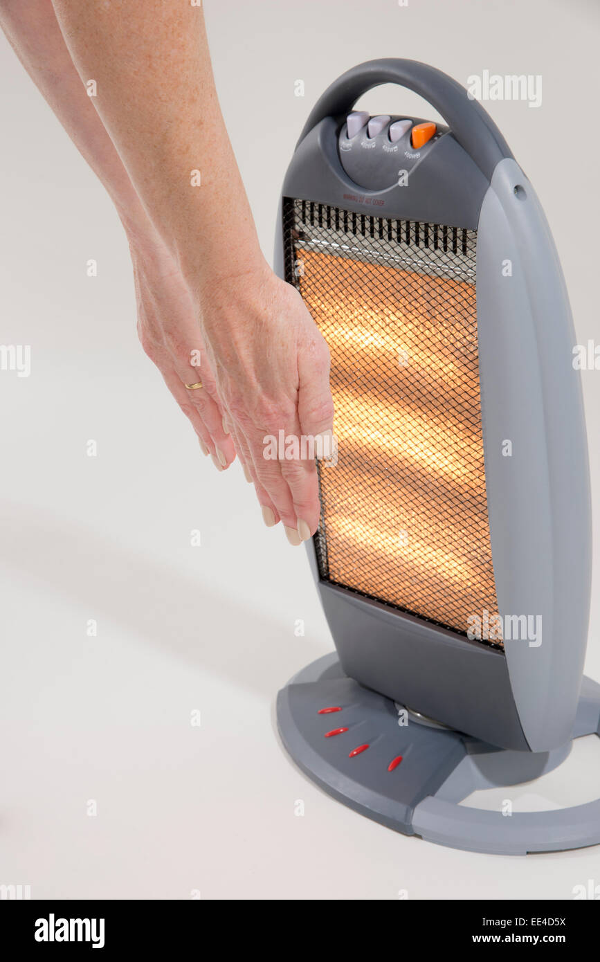 Donna mani di riscaldamento da un incendio elettrico Foto Stock