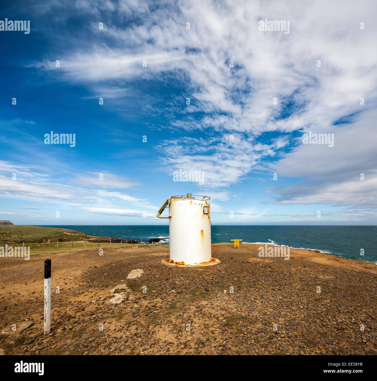Nuova Zelanda punto di pendenza, il vero punto più australe sulla terraferma in Nuova Zelanda con marcatore geodetici, faro e il cartello giallo. Foto Stock