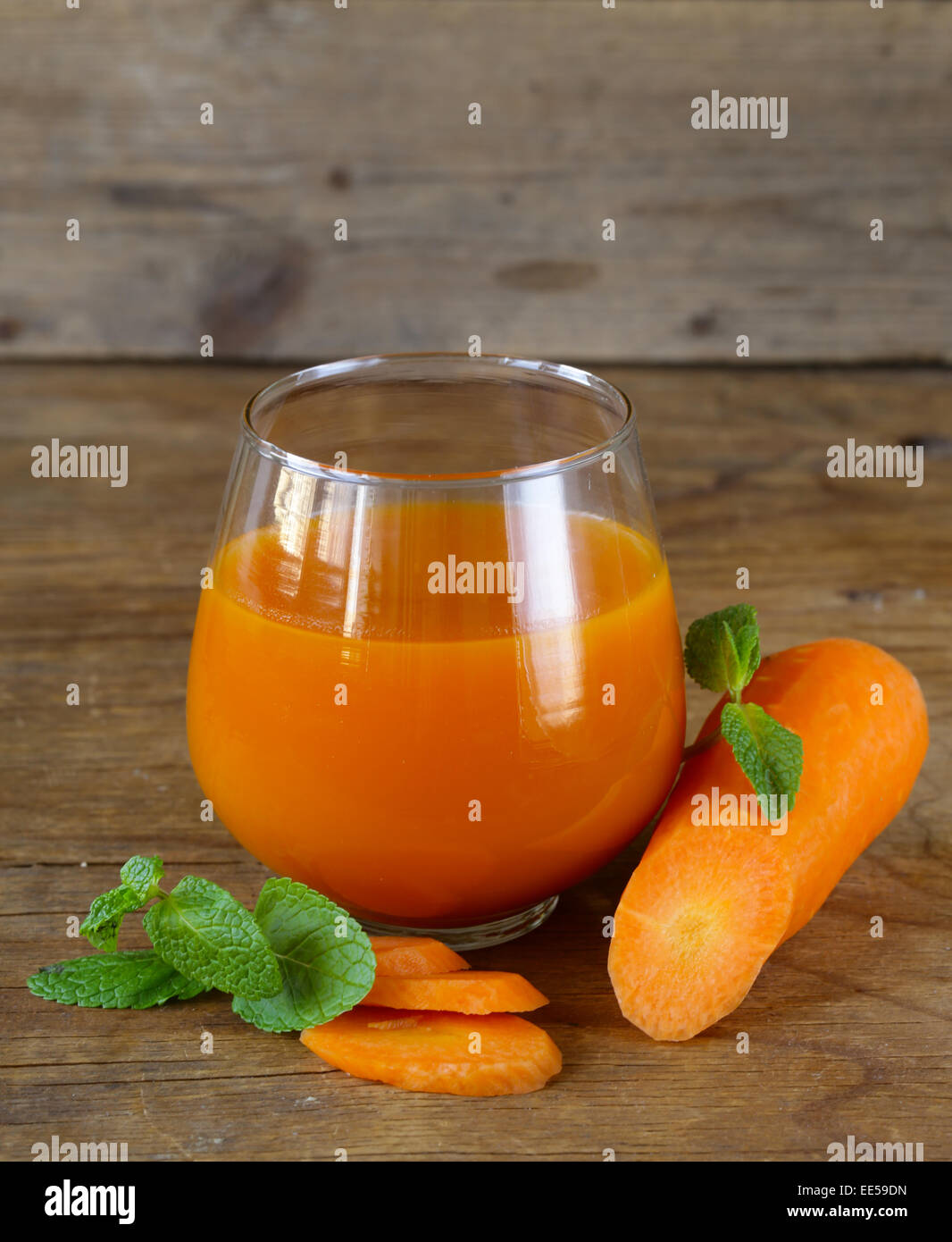 Fresco di succo di carota in vetro su un tavolo di legno Foto Stock