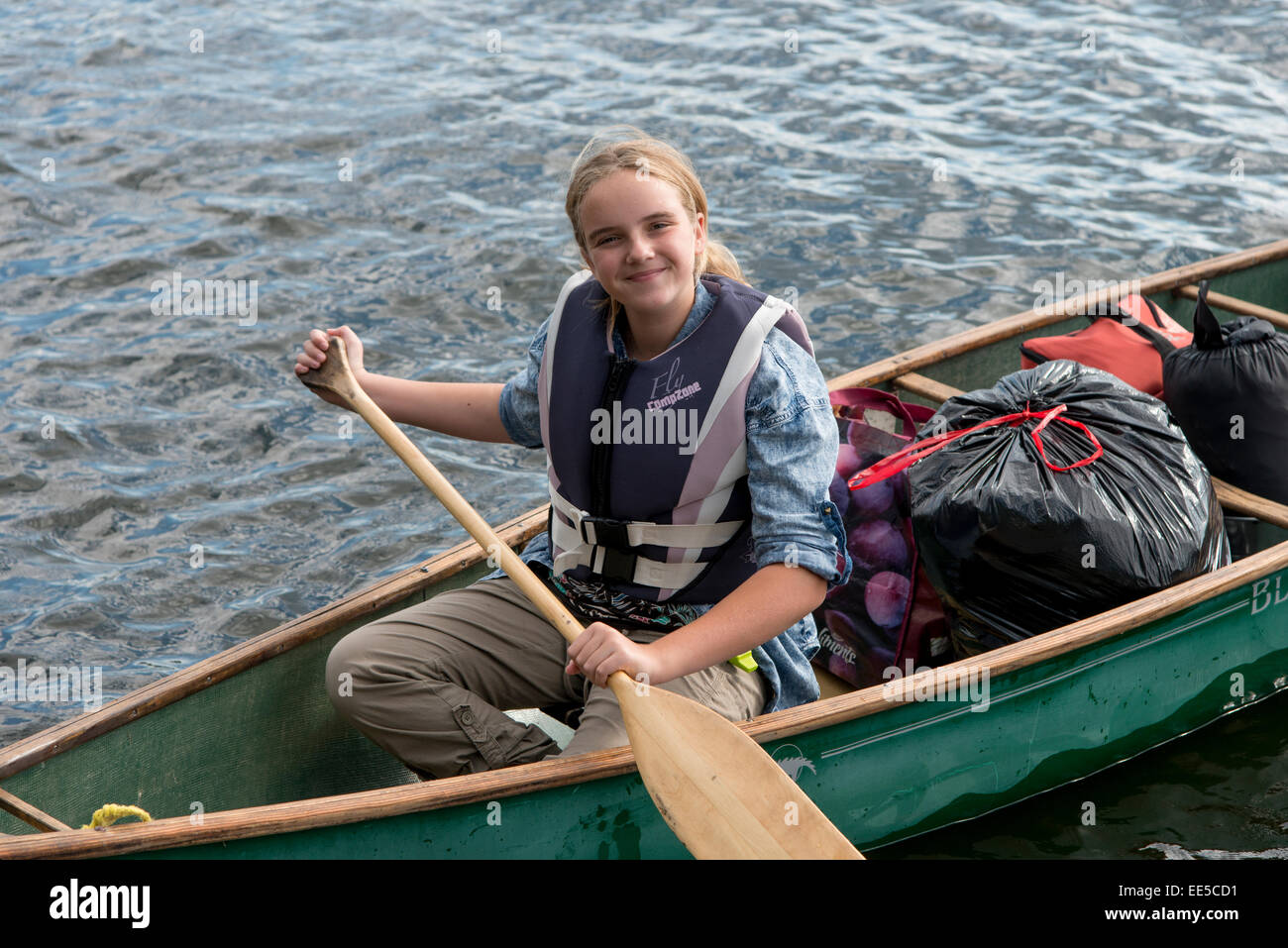 Ragazza remare una barca in un lago, il lago dei boschi, Ontario, Canada Foto Stock