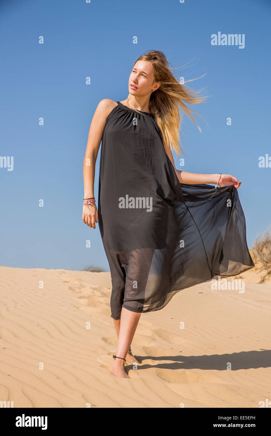 La donna nel lungo abito nero sulla spiaggia Modello rilasciato Foto Stock
