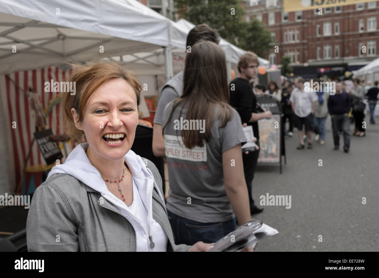 Un sorridente leafleter donna attraente a distribuire volantini a London street fair. Foto Stock