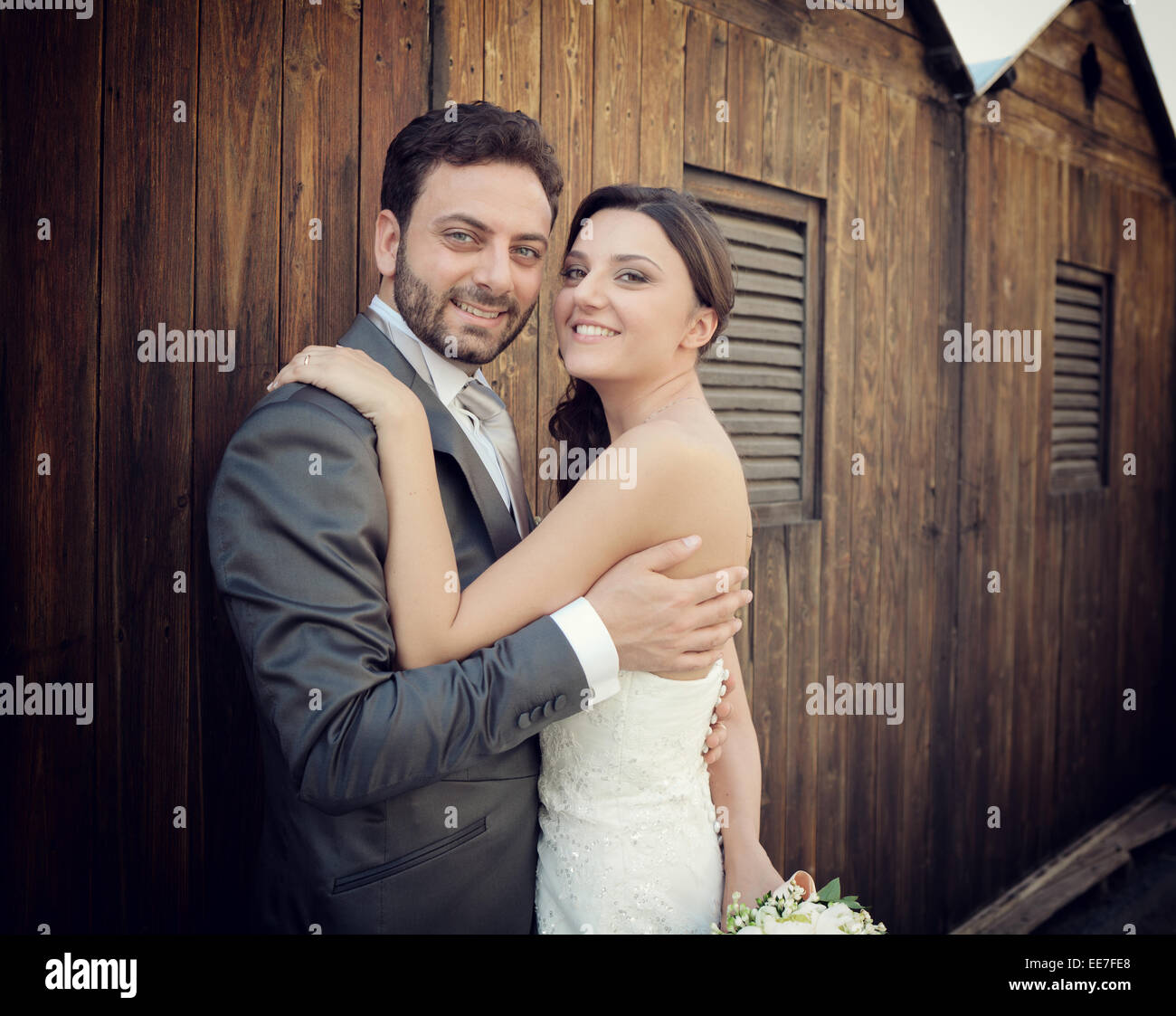 Coppia sposata nel giorno del loro matrimonio in prossimità di cabine di legno Foto Stock