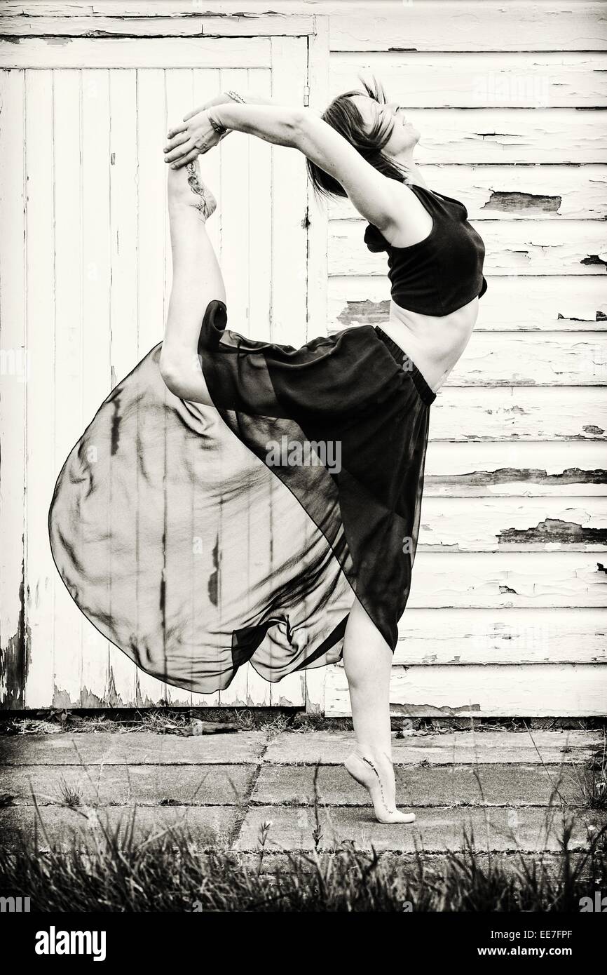 Ballerino femmina si riscalda al di fuori su lastre in calcestruzzo, di fronte a un capannone. Foto Stock