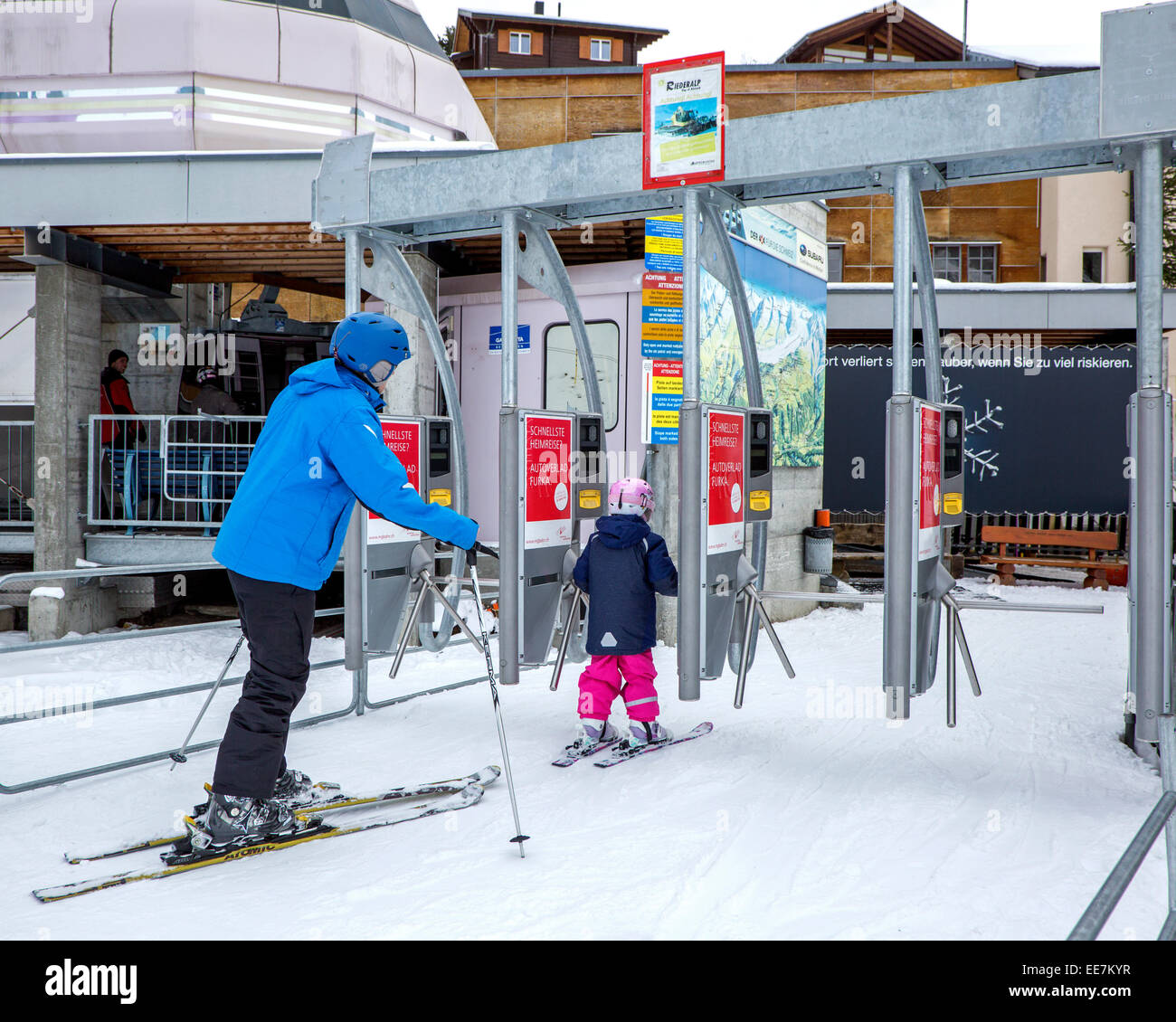 Sci di padre e figlio con caschi sci, entrando in stazione gondola al winter sports resort Riederalp, Wallis / Valais, Svizzera Foto Stock