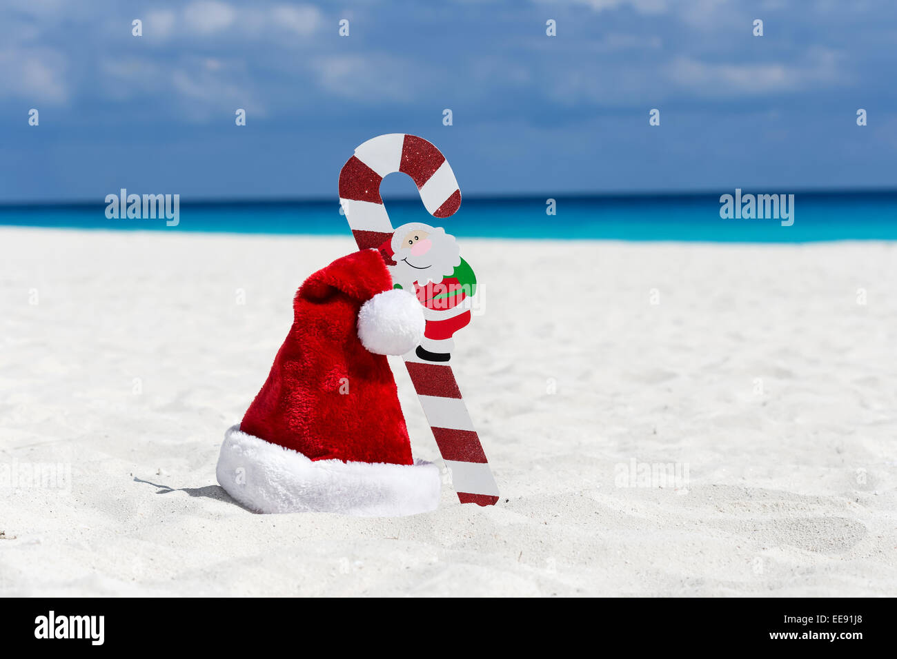 Santa Claus hat e della canna da zucchero in corrispondenza dei caraibi spiaggia sabbiosa, Cancun. Concetto di vacanza Foto Stock