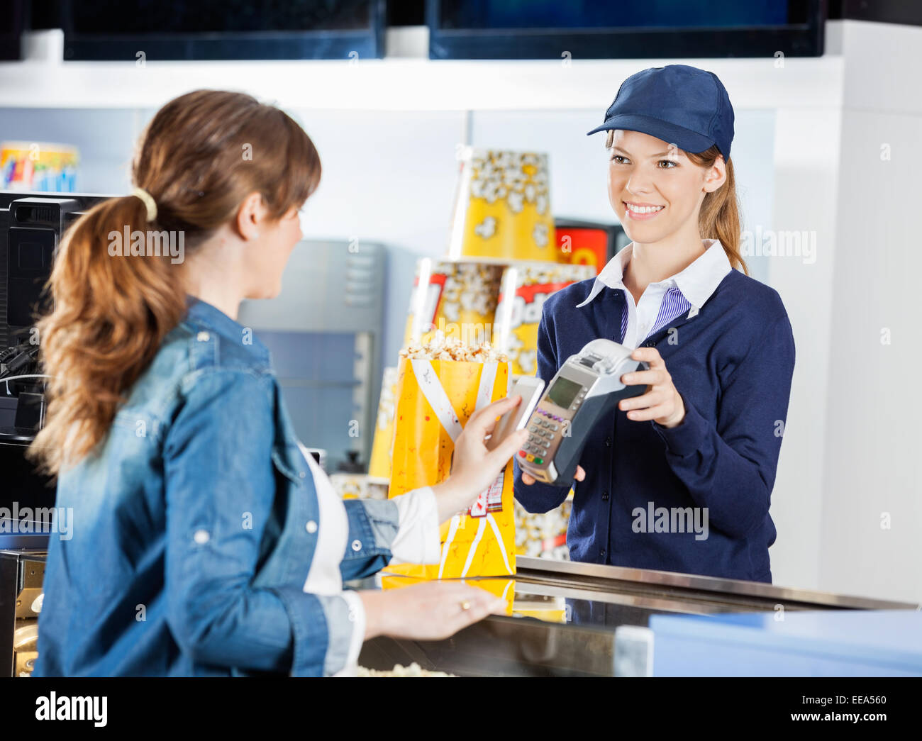 Lavoratore di accettare il pagamento da donna attraverso la tecnologia NFC a ci Foto Stock