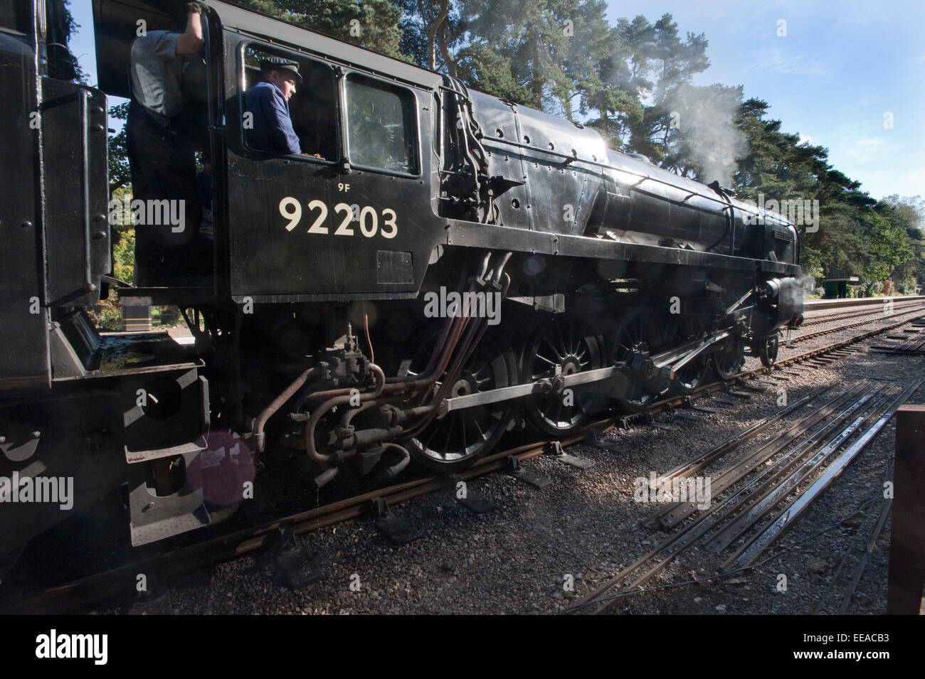 Il driver di 9F 2-10-0 locomotiva a vapore numero 92203 'Principe Nero' controlla la strada che corre intorno al suo treno alla stazione di Holt sul North Norfolk ferrovia fra Holt e Sheringham, vicino a Norwich. Foto Stock