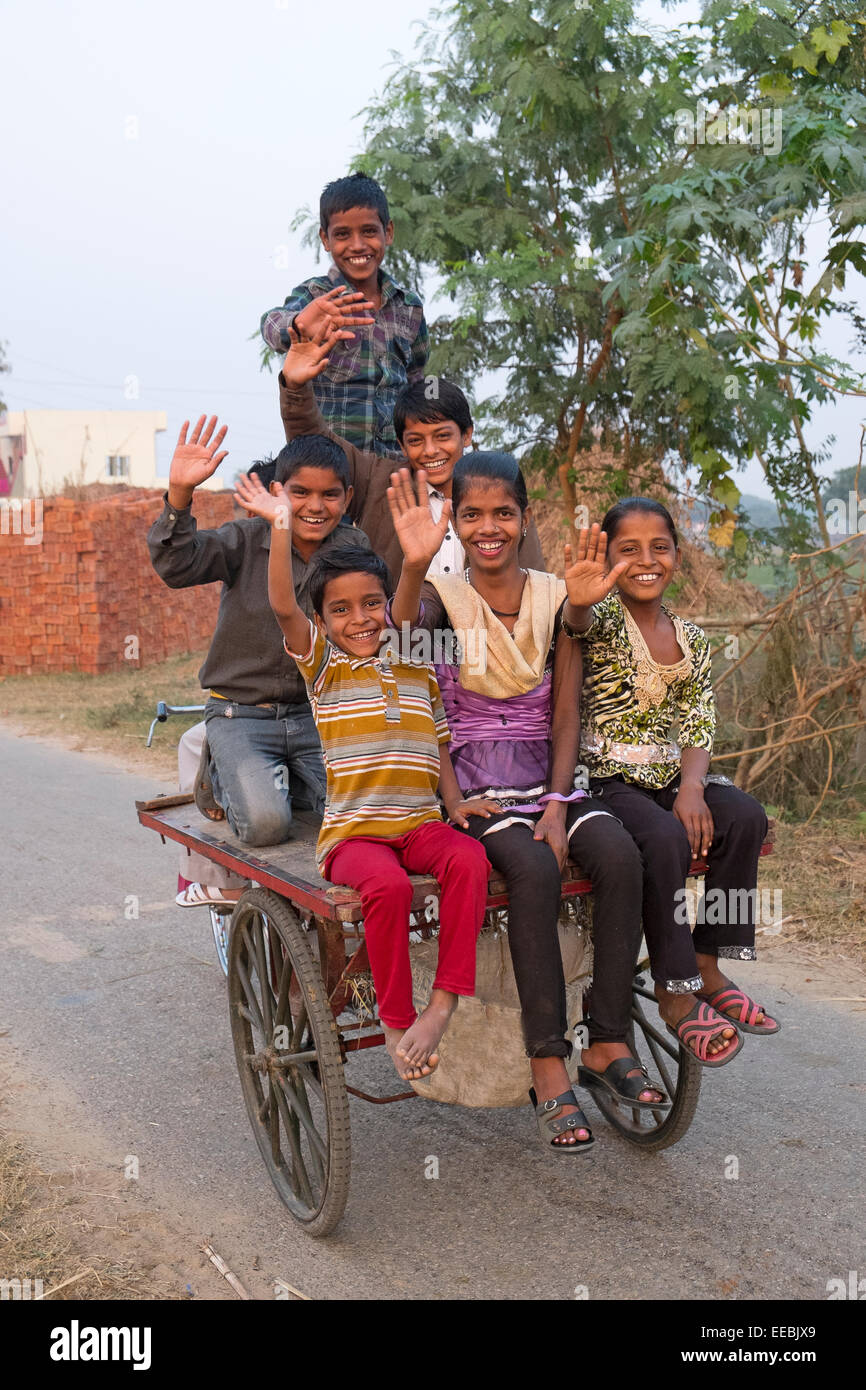 India, Uttar Pradesh, Agra, equitazione per bambini sul retro di un rimorchio per biciclette sventolando in telecamera Foto Stock