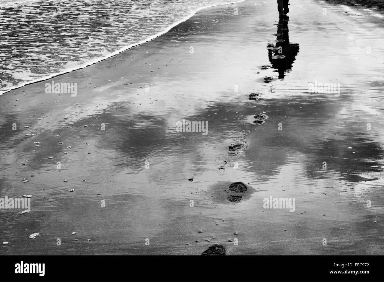 Orme nella sabbia vicino al mare con la bassa marea. Regno Unito. In bianco e nero Foto Stock