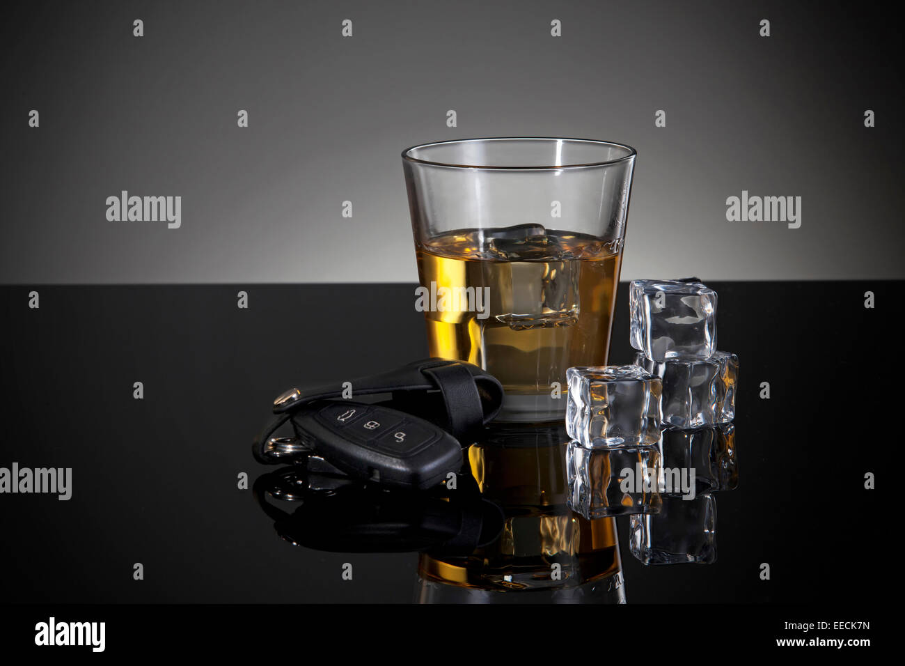 Una chiave auto in primo piano e un bicchiere di whiskey dietro. Foto Stock