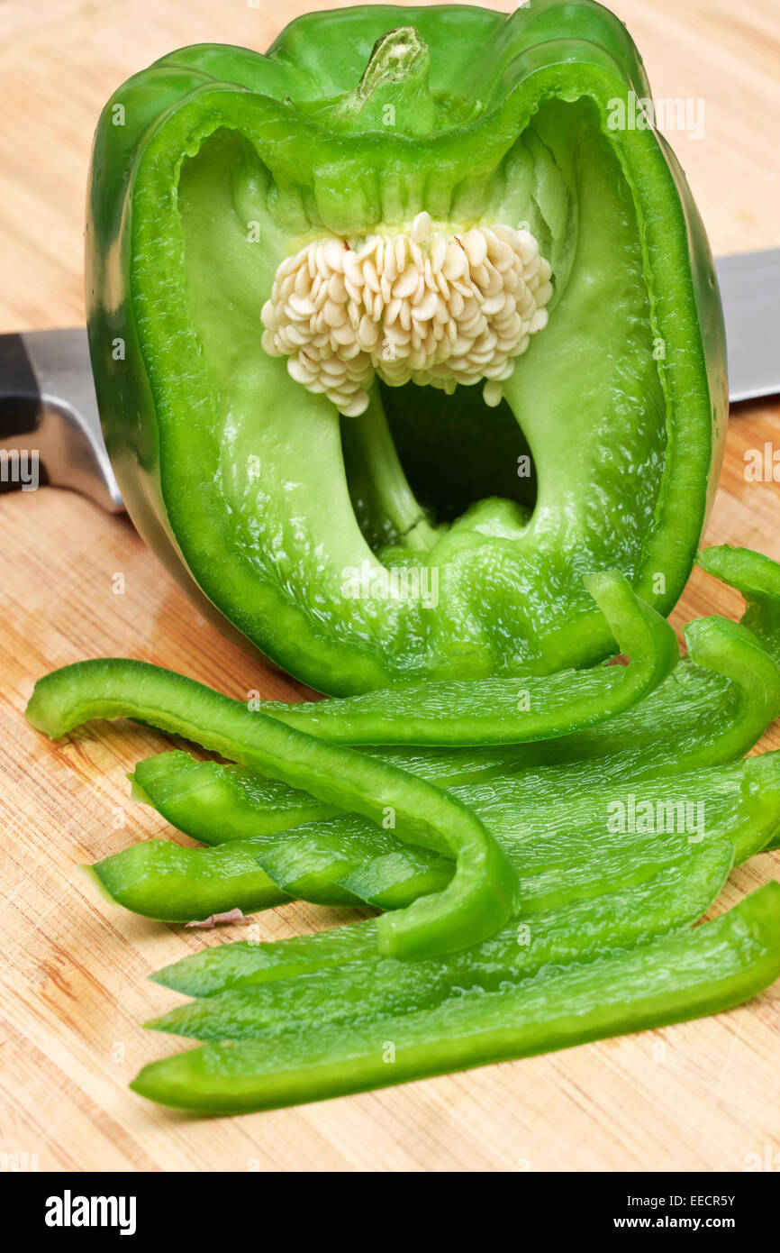 Peperone verde con la metà tagliata in strisce su legno tagliere con Coltello per cuoco. Foto Stock