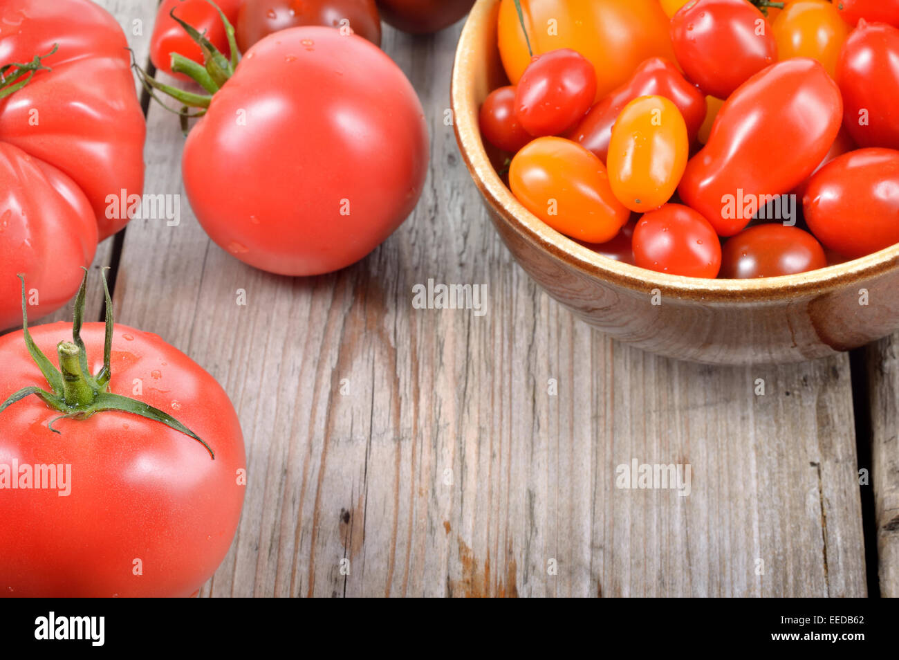 Colorato diverso tipo i pomodori in una ciotola sul tavolo di legno. Rosso, Giallo, grandi e piccoli pomodori. Copyspace. Paesi del Mediterraneo e del egli Foto Stock