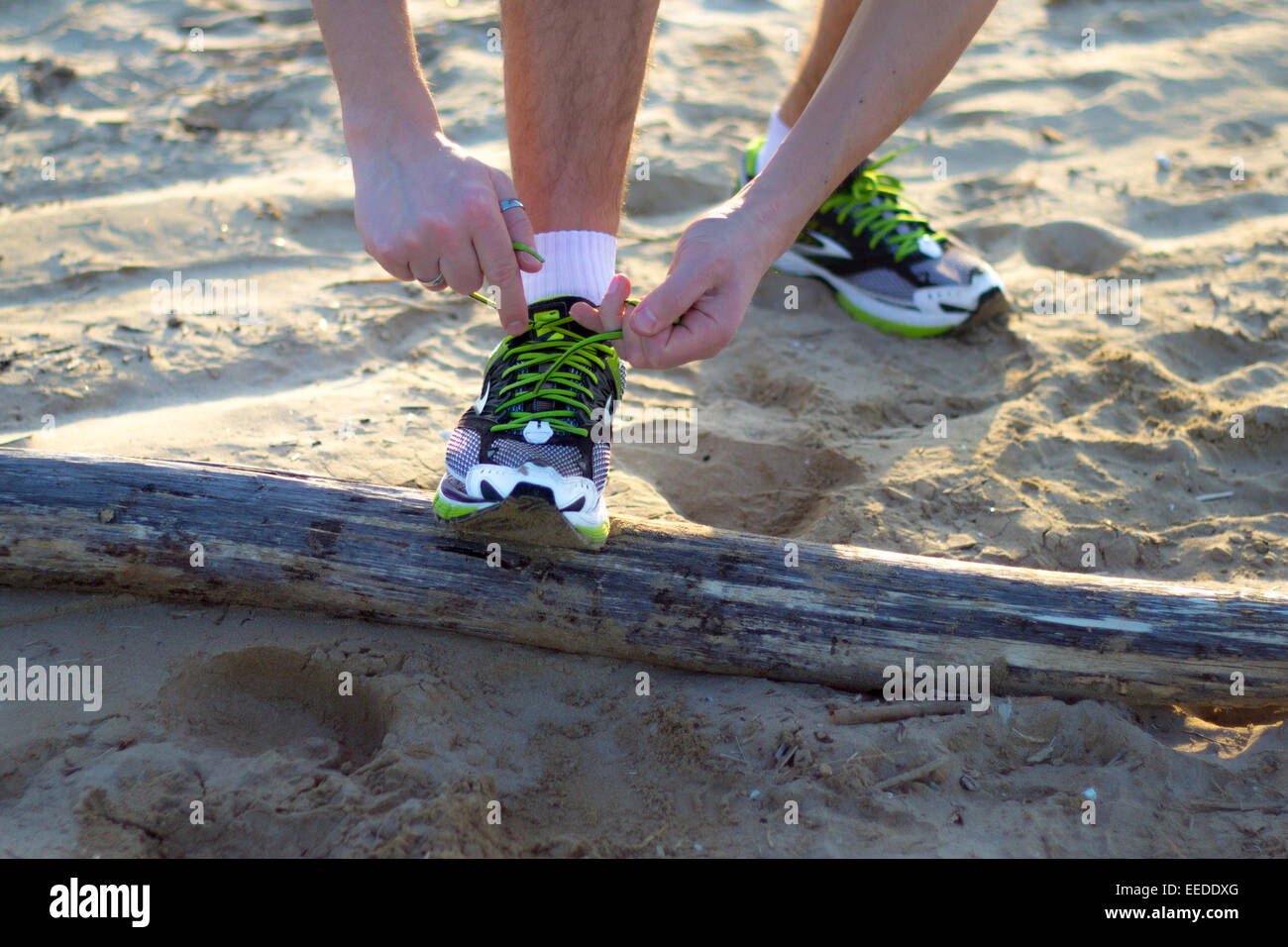 Uomo in spiaggia che si fissano le scarpe prima di uno sport Foto Stock