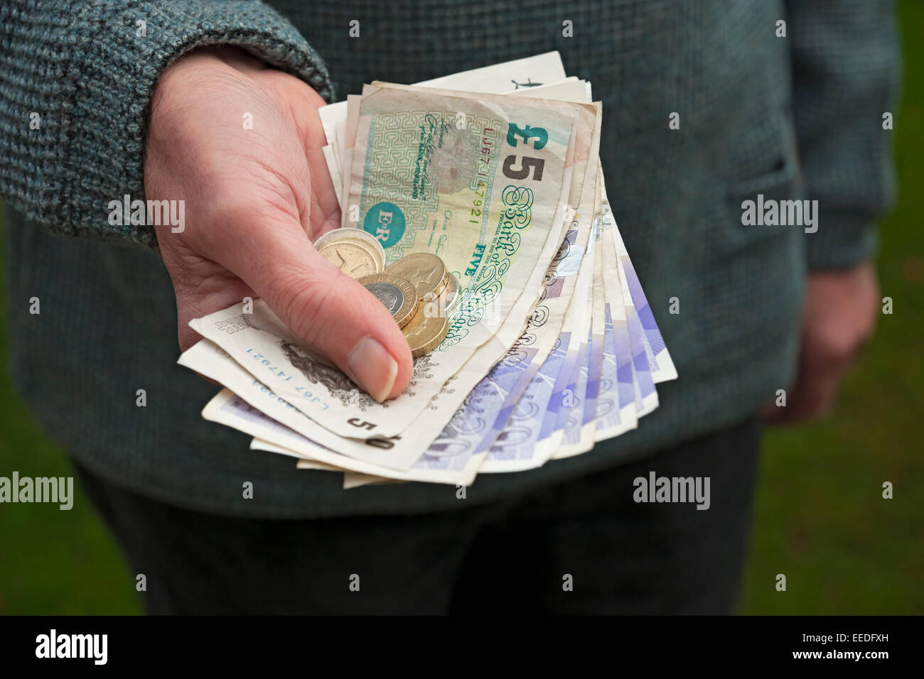 Primo piano di un uomo che detiene il concetto aziendale di moneta inglese banconote e monete in contanti Inghilterra Regno Unito Regno Unito Gran Bretagna Gran Bretagna Foto Stock