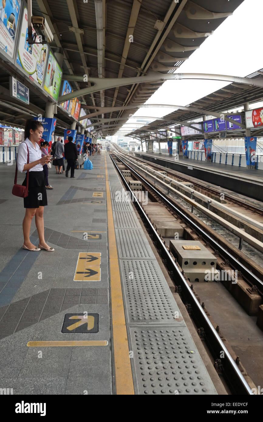 Asian giovane donna in attesa alla stazione di Sathorn, trasporto pubblico urbano stazione dello skytrain, Bangkok, Thailandia, Sud-est asiatico. Foto Stock