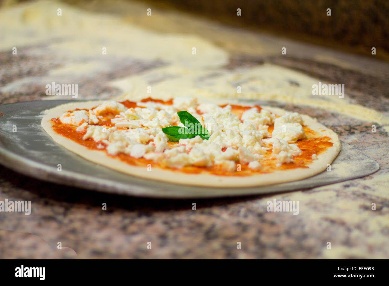 La lavorazione della pizza. Italian pizza chef mette sulla pala pizza e cuocere Foto Stock