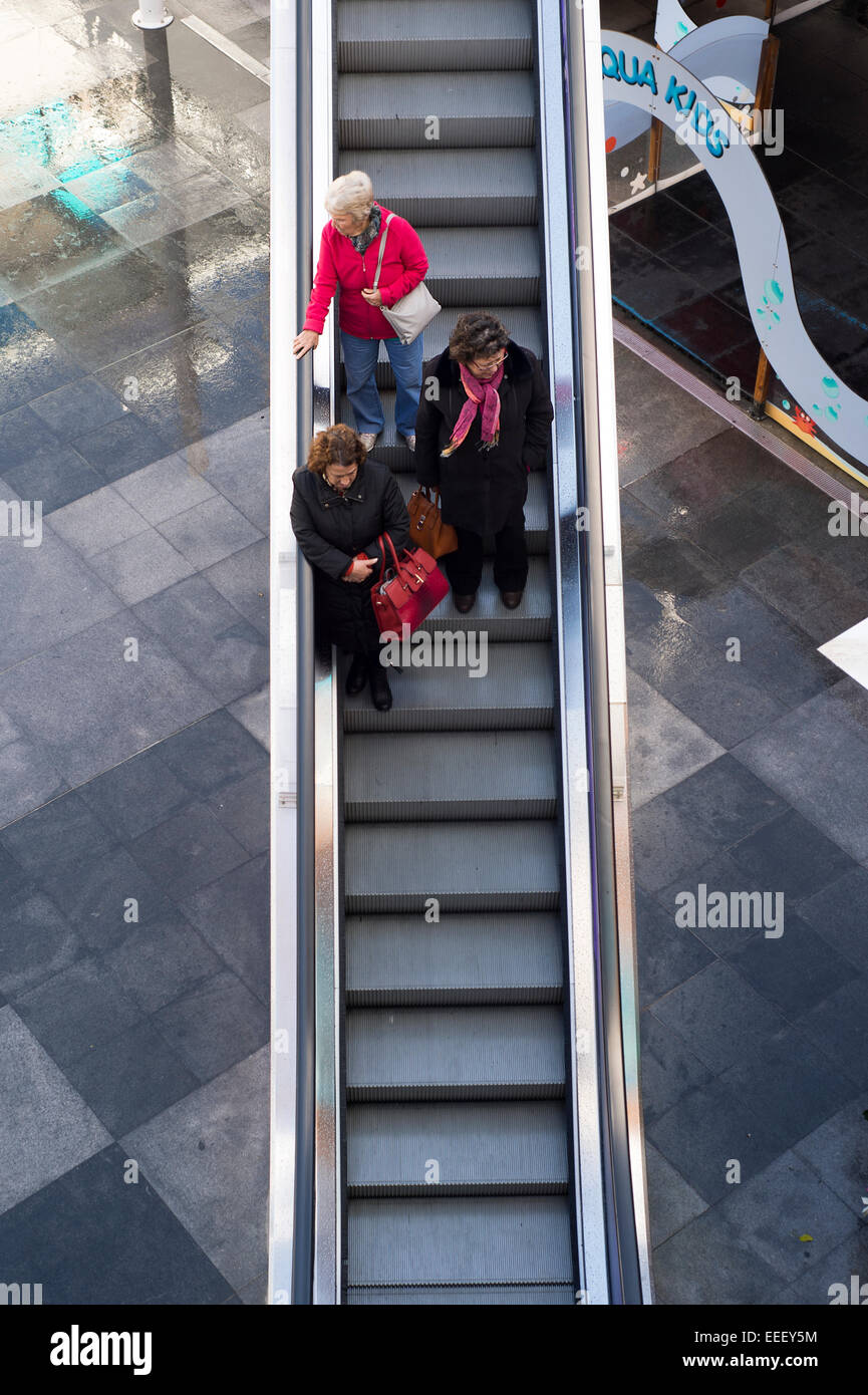 Le donne in piedi su una scala mobile verso il basso in un centro commerciale per lo shopping Foto Stock
