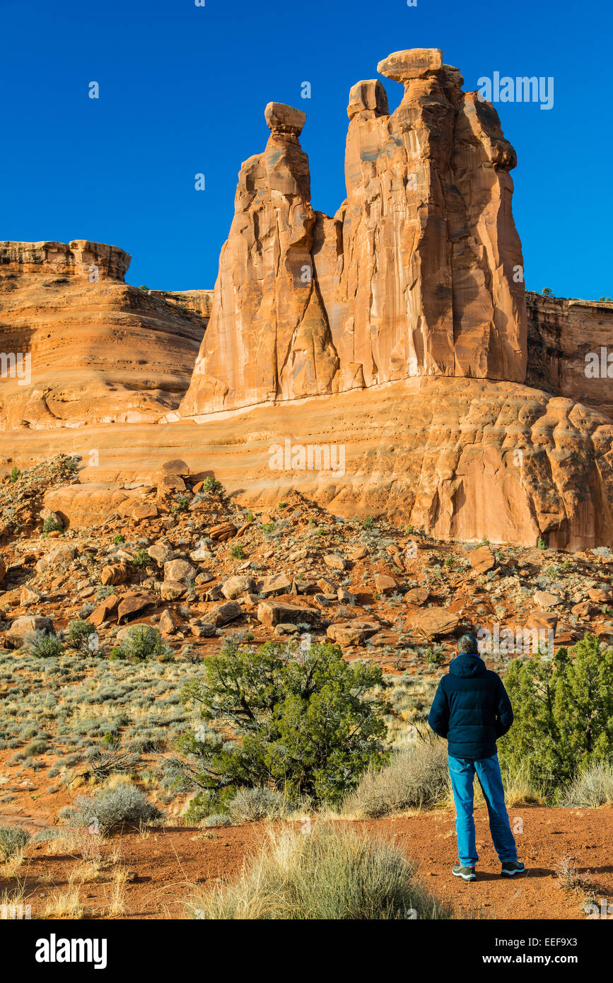 Maschio caucasico tourist guardando i tre pettegolezzi torre in pietra arenaria, Arches National Park, Utah, Stati Uniti d'America Foto Stock