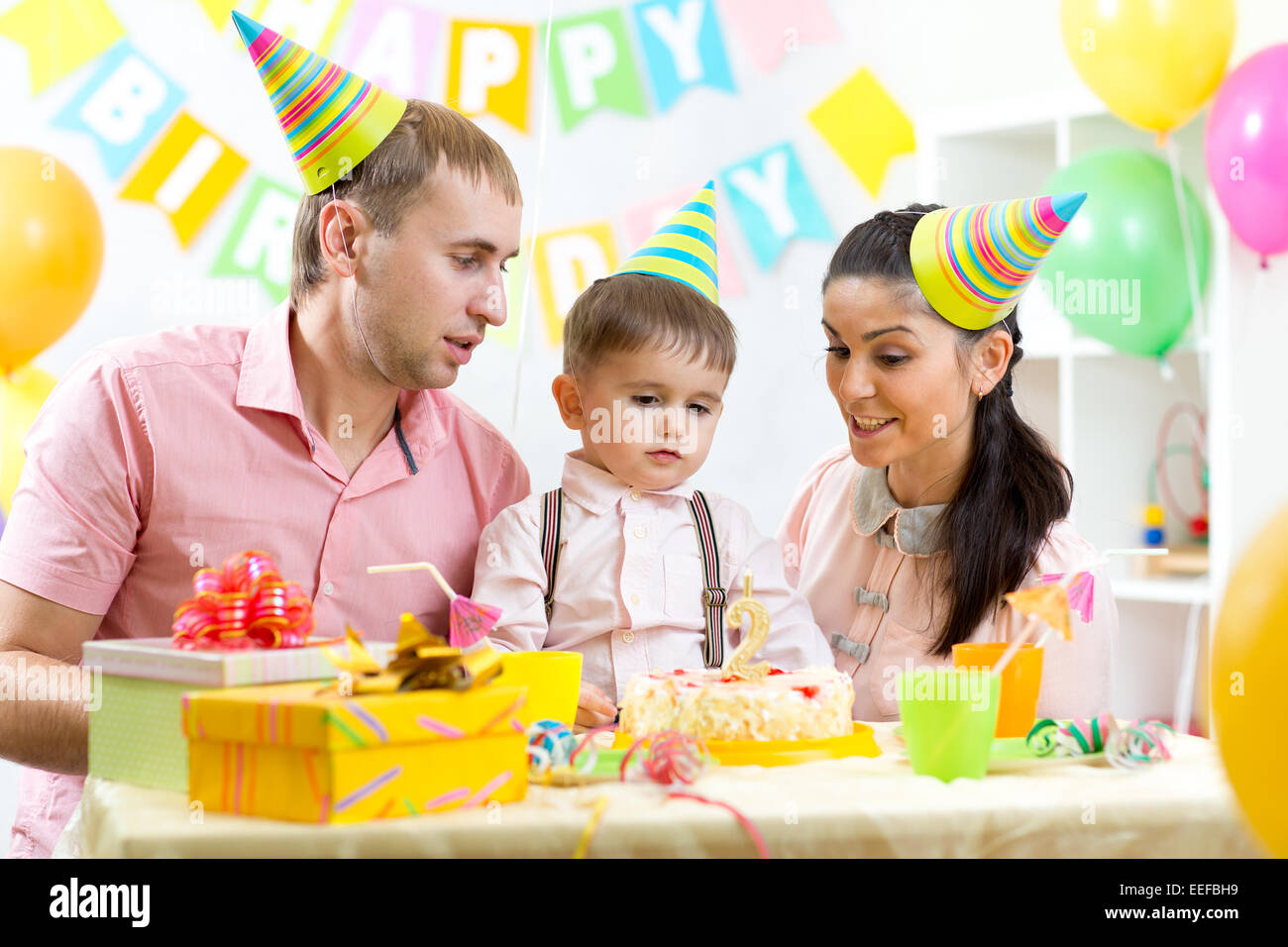 Il capretto con i genitori colpo candela sulla torta di compleanno Foto Stock