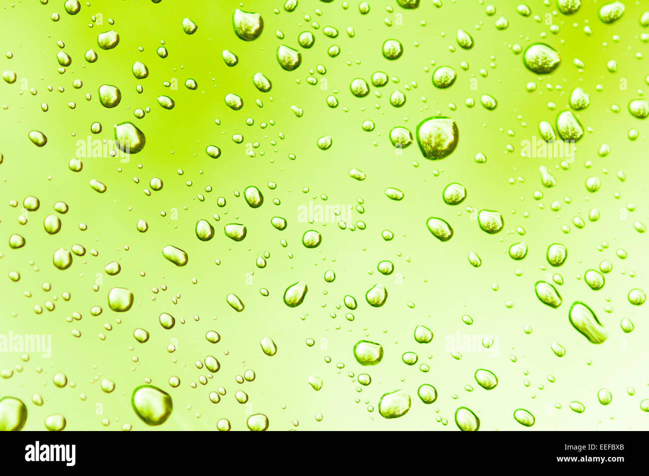 Le goccioline di acqua sul vetro chiari riflettono la luce ambiente produrre interessanti modelli. Foto Stock