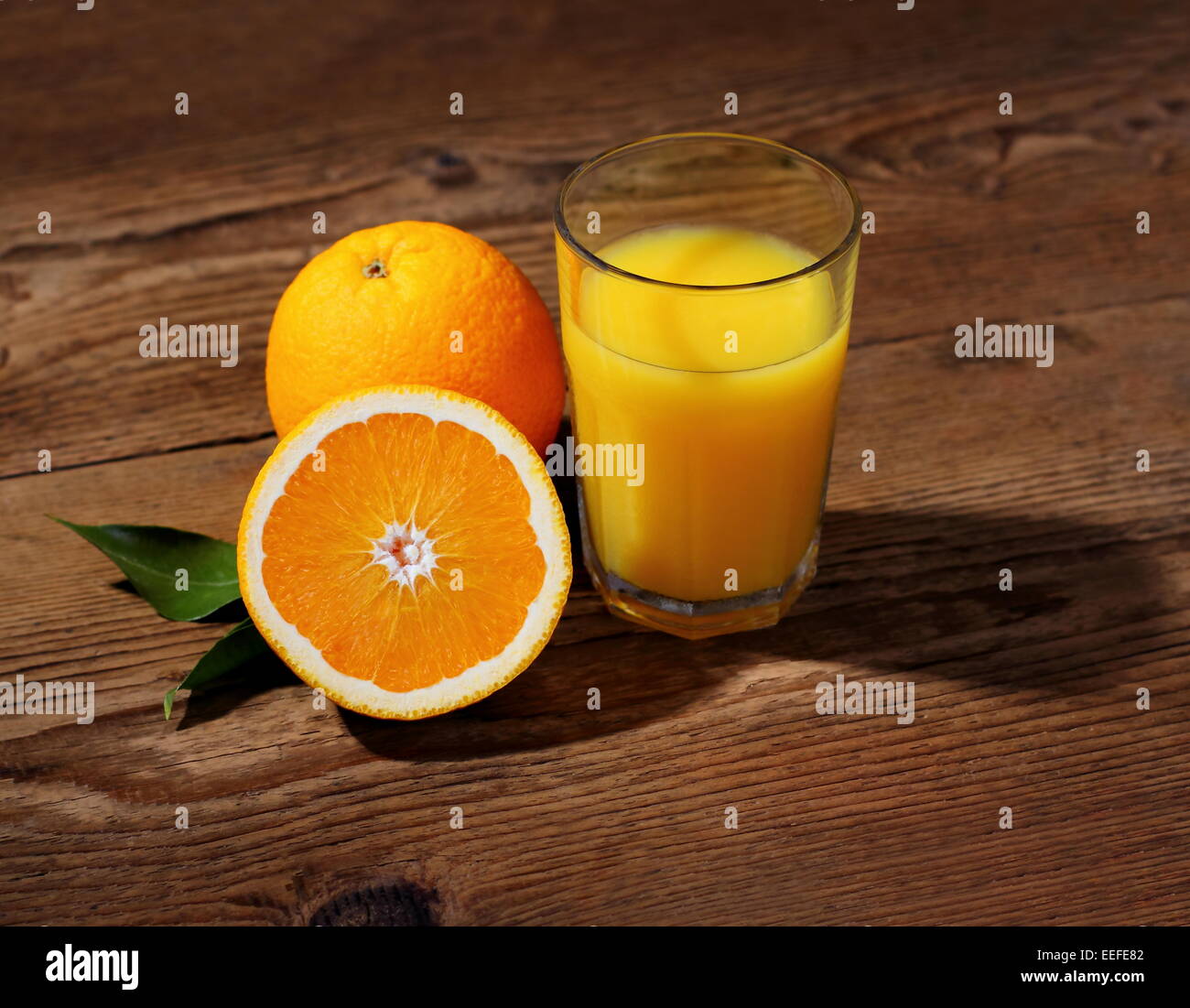 Arance mature di frutta e succhi di frutta in vetro su tavola di legno Foto Stock