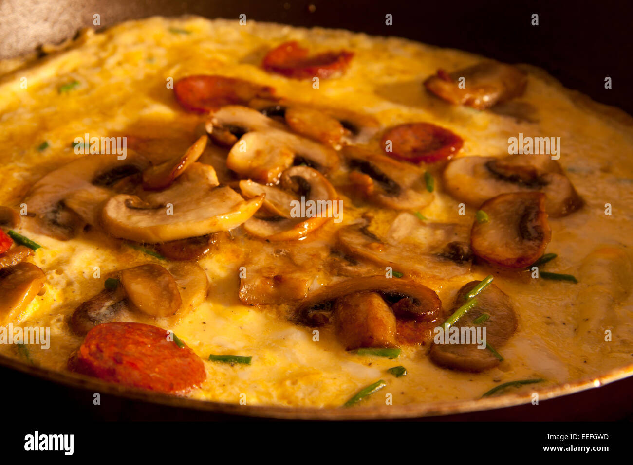 Preparato di fresco riempito di omelette con funghi e salame su una casa colonica tavola con il sole di mattina splendenti in. Foto Stock