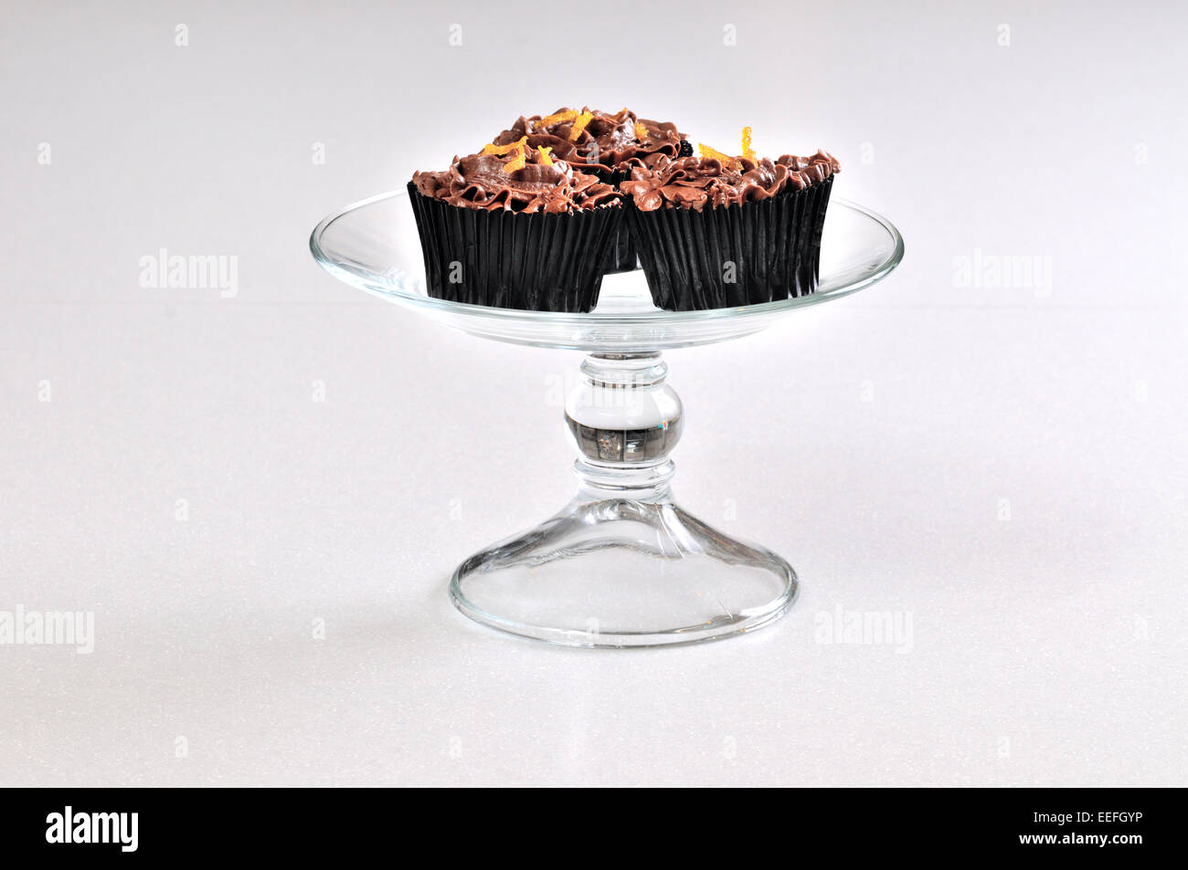 3 tazza di cioccolato torte con spruzzi di colore arancione su un piatto di vetro. Foto Stock