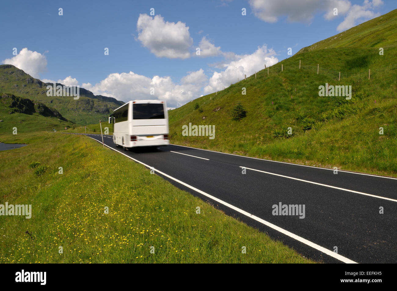 Bus bianco sulla strada di montagna nelle Highlands della Scozia. Foto Stock