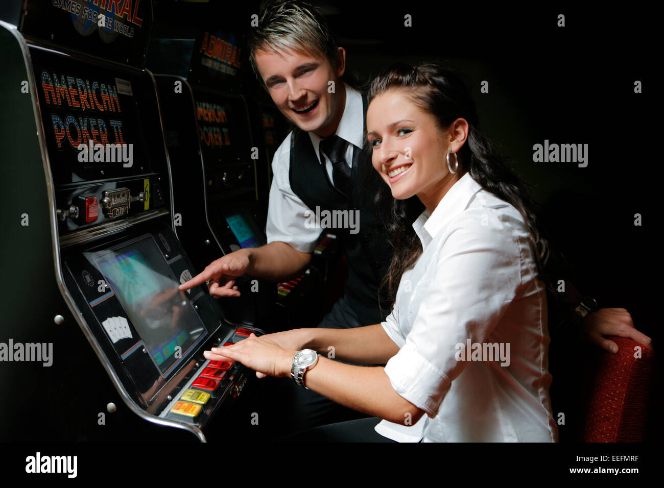 Junges Paar spielt un einem Spielautomaten Foto Stock