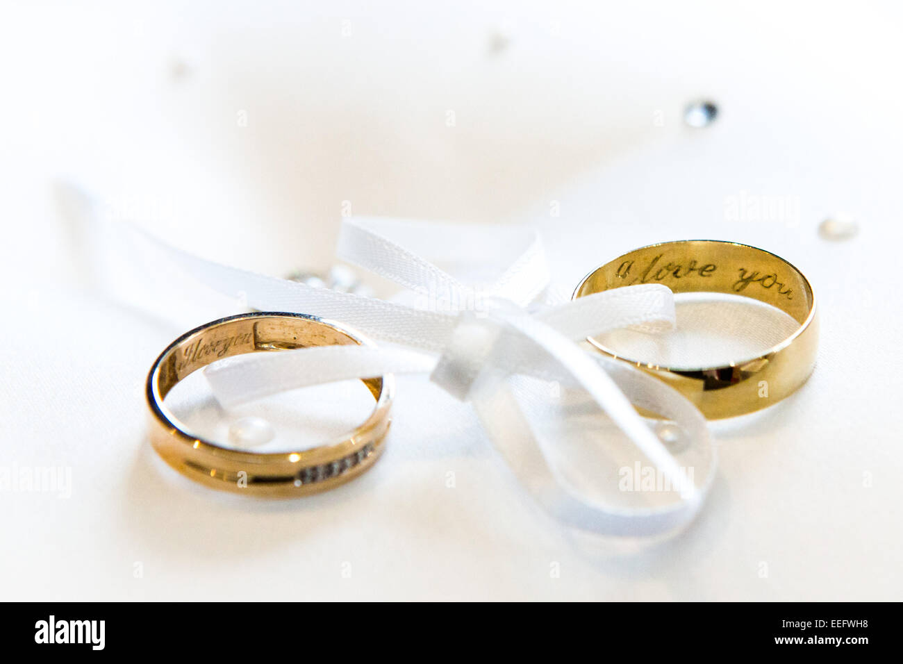 Nastro bianco unendo due anelli di nozze con ti amo inscritto Foto Stock