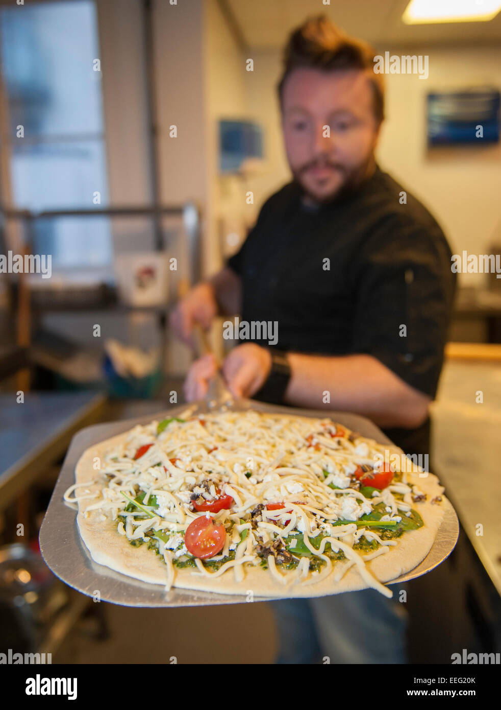 Un baker con una pizza su una pala di pelatura Foto Stock