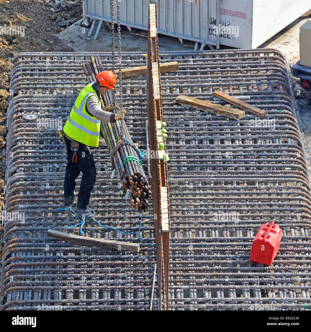 Steelfixer guidare una gru bundle di abbassamento dei tondini di acciaio sul telaio di fondazione sito in costruzione Londra Inghilterra REGNO UNITO Foto Stock