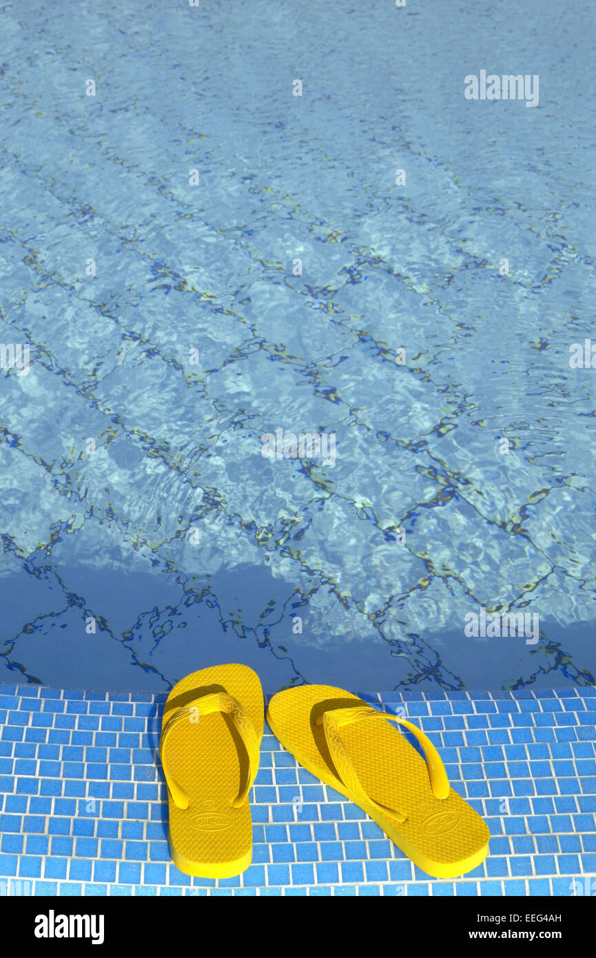 Aussen Piscina Schuhe Badeschuhe flip-flops Farbe Gelb Poolrand Wasser Blau Sommer Urlaub Freizeit Holiday Swimmingpool Konzepte St Foto Stock