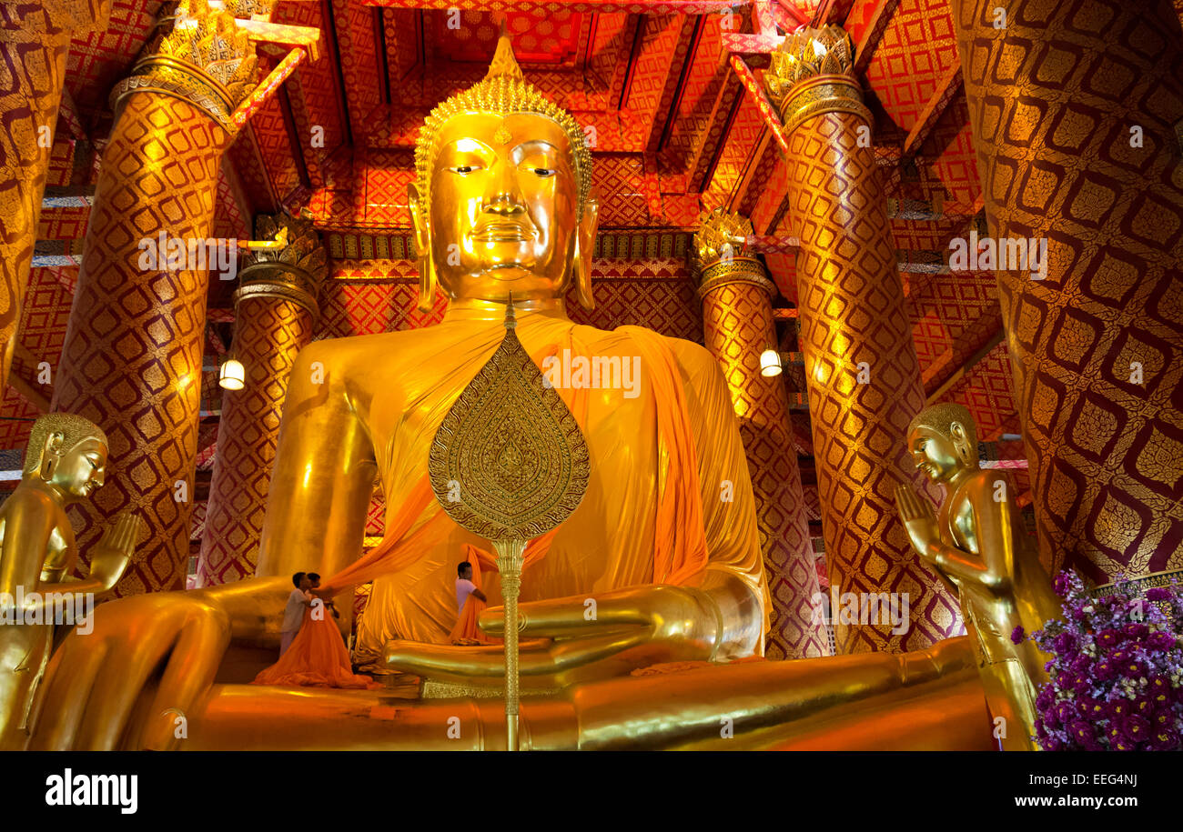 Thailandia - Lavoratori il sollevamento le offerte di lunga foulard arancione su il Buddha per una cerimonia religiosa al Wat Phanan Choeng. Foto Stock