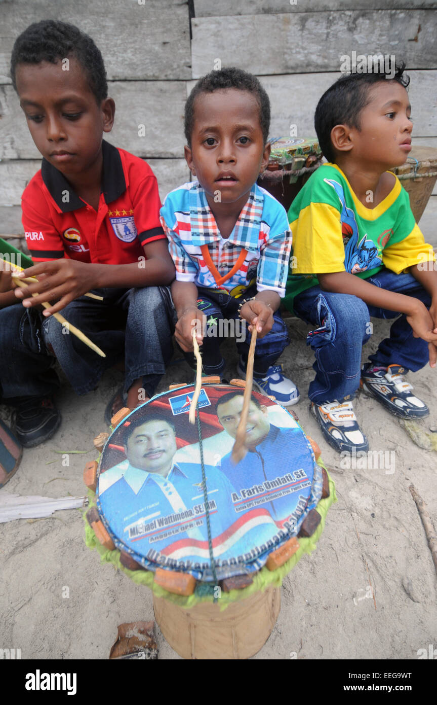 I bambini con fatti in casa il tamburo dotato di locali di candidati politici' volti, Yenbeser village, Raja Ampat, provincia di Papua, Indonesia. N. Foto Stock