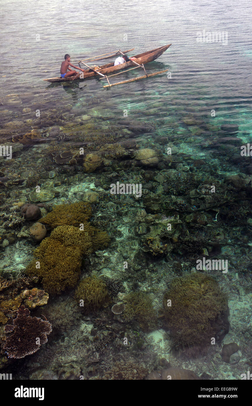 Bambini pesca dal piccolo vecchio piroga, Isola di Gam, Raja Ampat, provincia di Papua, Indonesia. No signor Foto Stock