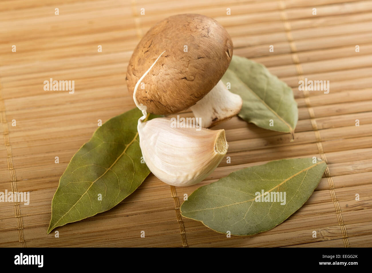 Foglie di alloro con l'aglio e i funghi sul tappetino di bambù Foto Stock