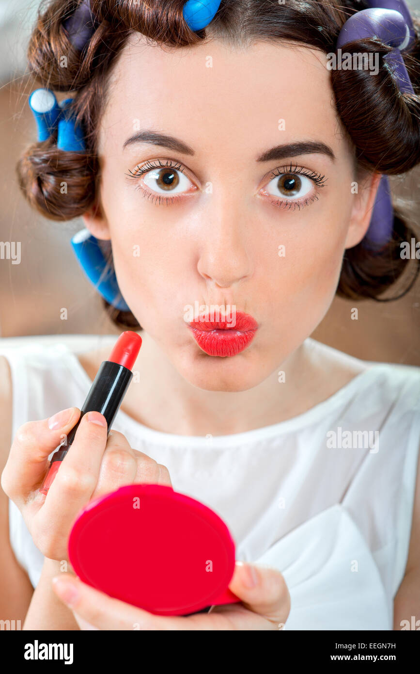 Donna sorridente con arricciacapelli con un rossetto rosso Foto Stock