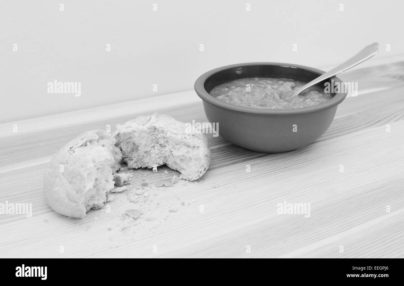 Zuppa servita con un cilindro di pane croccante strappata in due con copia spazio - elaborazione monocromatica Foto Stock