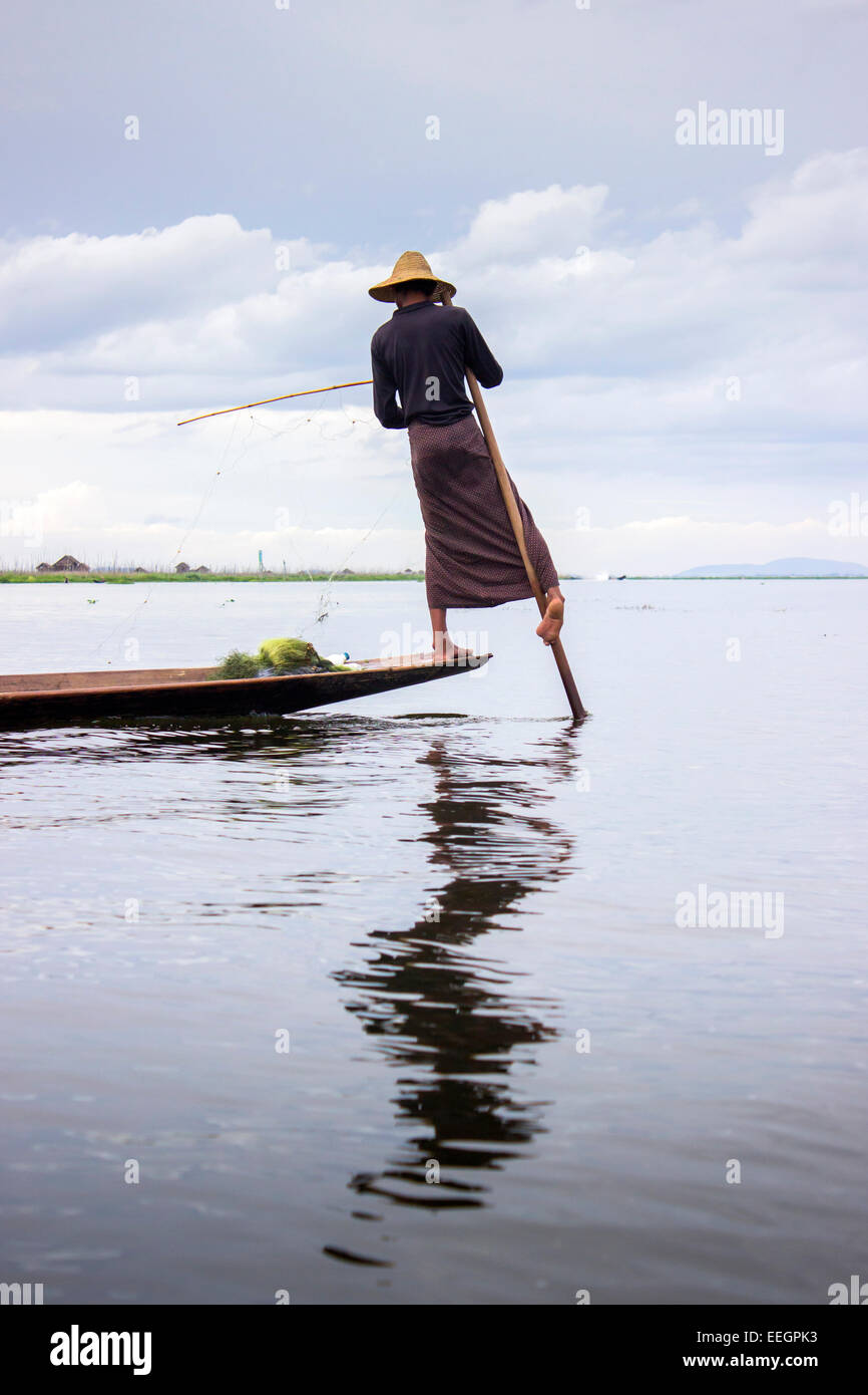 Un pescatore è la pesca con reti da sua canoa pagaiata i cuori con la sua gamba, Lago Inle, MYANMAR Birmania, sud est asiatico Foto Stock