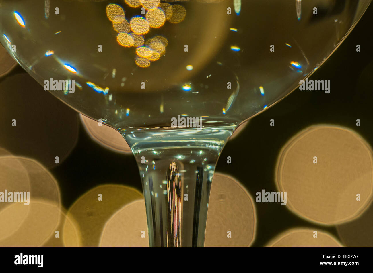 Una fotografia macro dello stelo e la coppa di un vino bianco di vetro con luci scintillanti in background Foto Stock