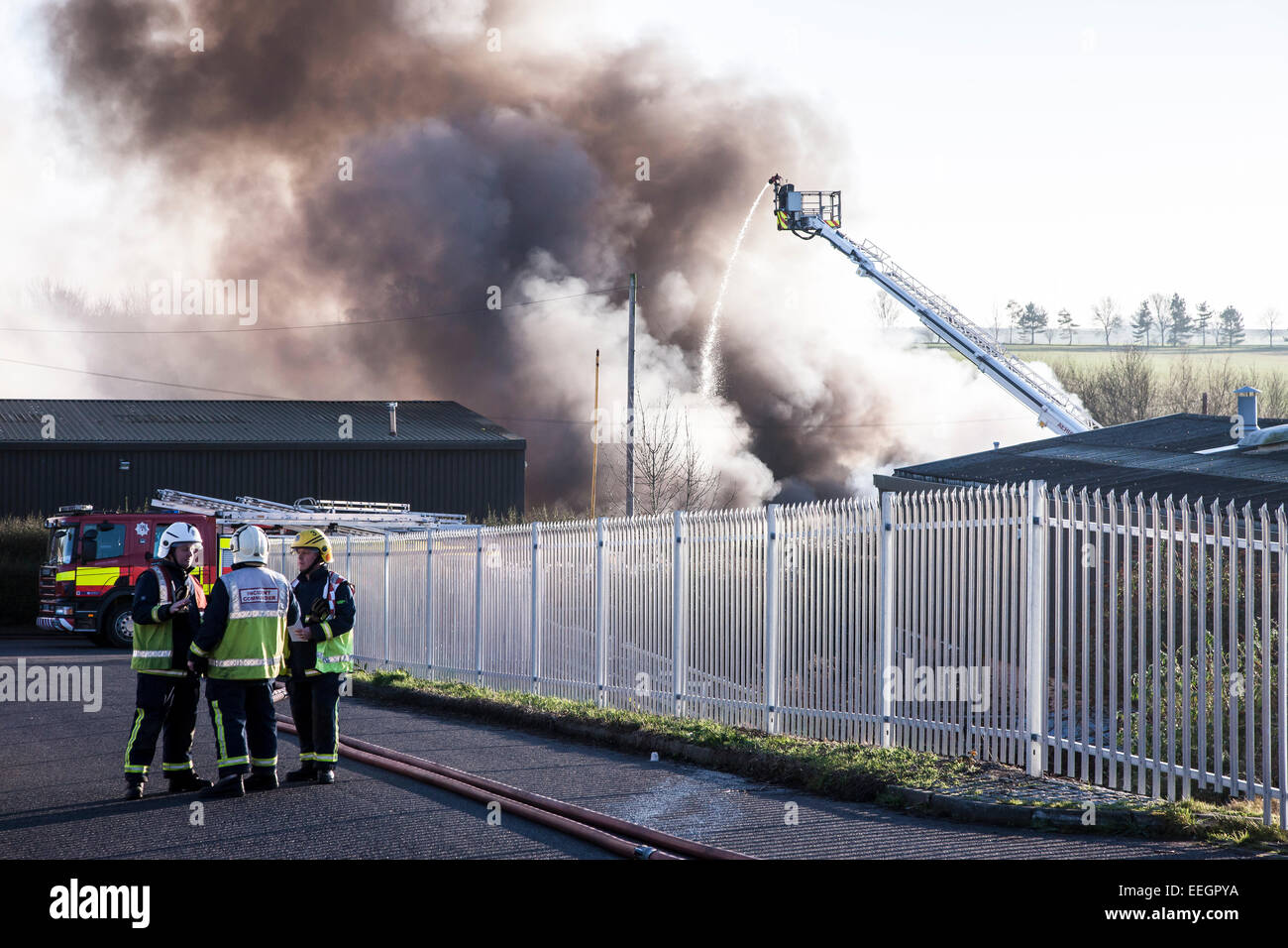 Northamptonshire. U.K. 18 gennaio 2015. Il grande fuoco a pensare verde il riciclaggio Ltd, Wollaston Industrial Estate, Raymond vicino, Wollaston. Trattamento e smaltimento di rifiuti pericolosi e non pericolosi è stata la masterizzazione poiché 1am quando l'allarme è stato sollevato, con molte apparecchiature antincendio in famigli. Il fumo potrebbe essere visto da circa 15 miglia di distanza, Foto Stock