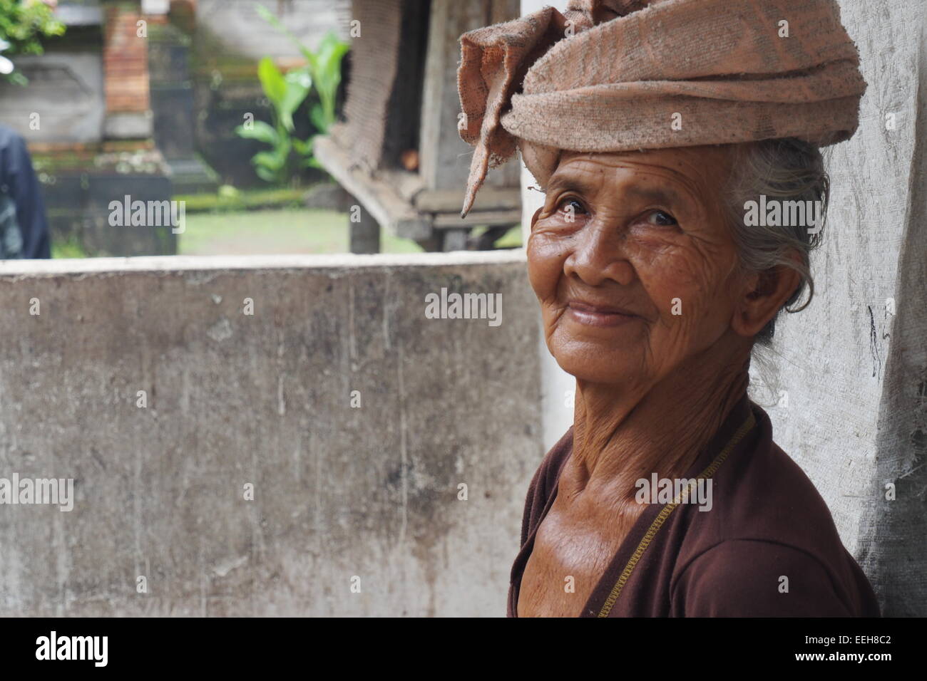 Anziana signora Balinese in abito tradizionale al di fuori di casa sua. Foto Stock