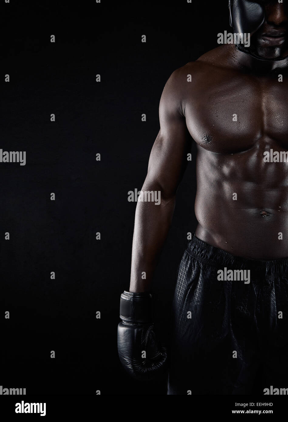 Un forte corpo di africani boxer maschio su sfondo nero con copia spazio. Immagine ritagliata maschile di boxe in ingranaggio con muscolare di b Foto Stock