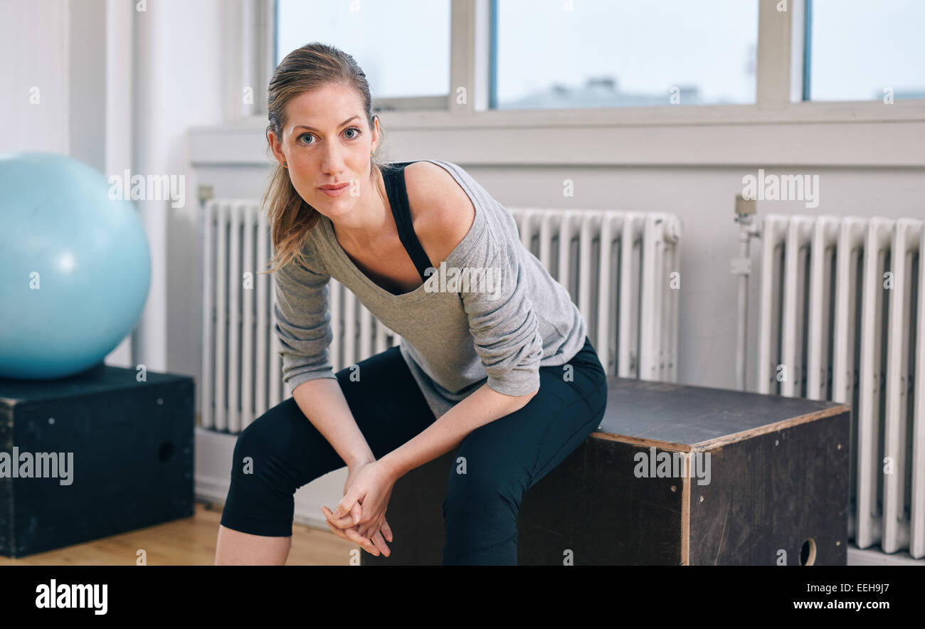 Ritratto di fiducia fitness trainer seduta in palestra. La donna caucasica rilassante dopo allenamento. Foto Stock